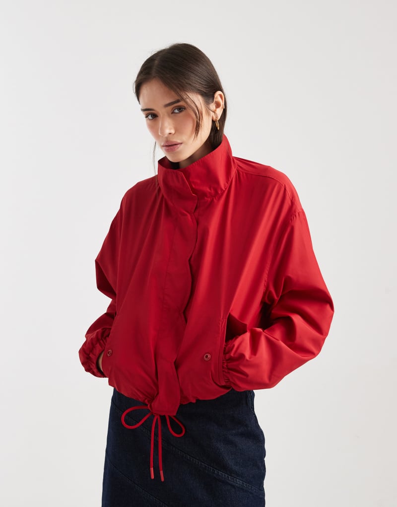 Fırfır detaylı, yüksek yakalı, kırmızı renkli rüzgarlık ceket.